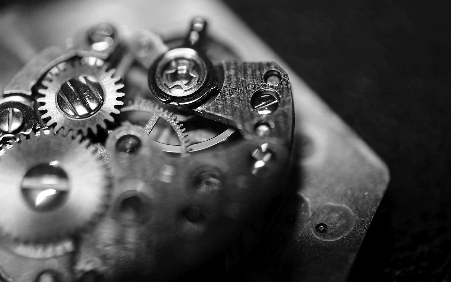 Détail d'un mouvement horloger mécanique en noir et blanc, rouages et vis en gros plan