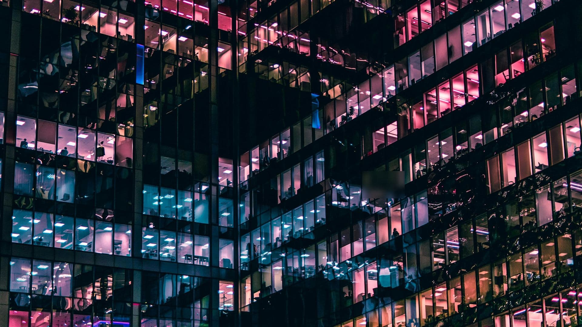 Façade vitrée d'une tour de bureaux la nuit, étages de plateaux éclairés