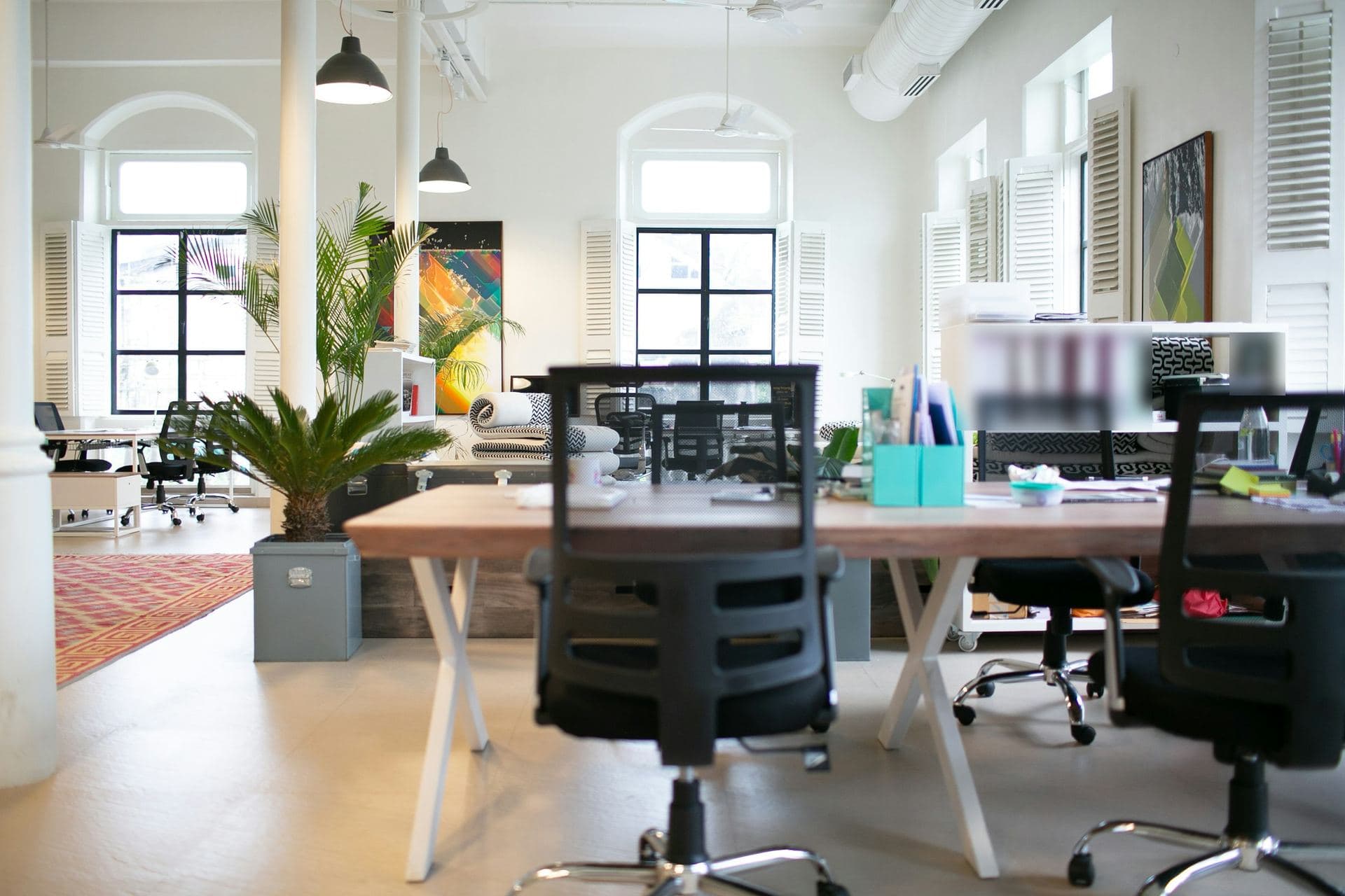 Plateau de travail lumineux aux fenêtres cintrées, grande table partagée et chaises vides