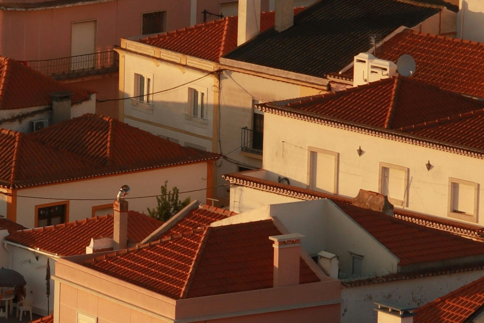 Toits de tuiles rondes et façades claires d'une ville du Sud, dans la lumière rasante du soir