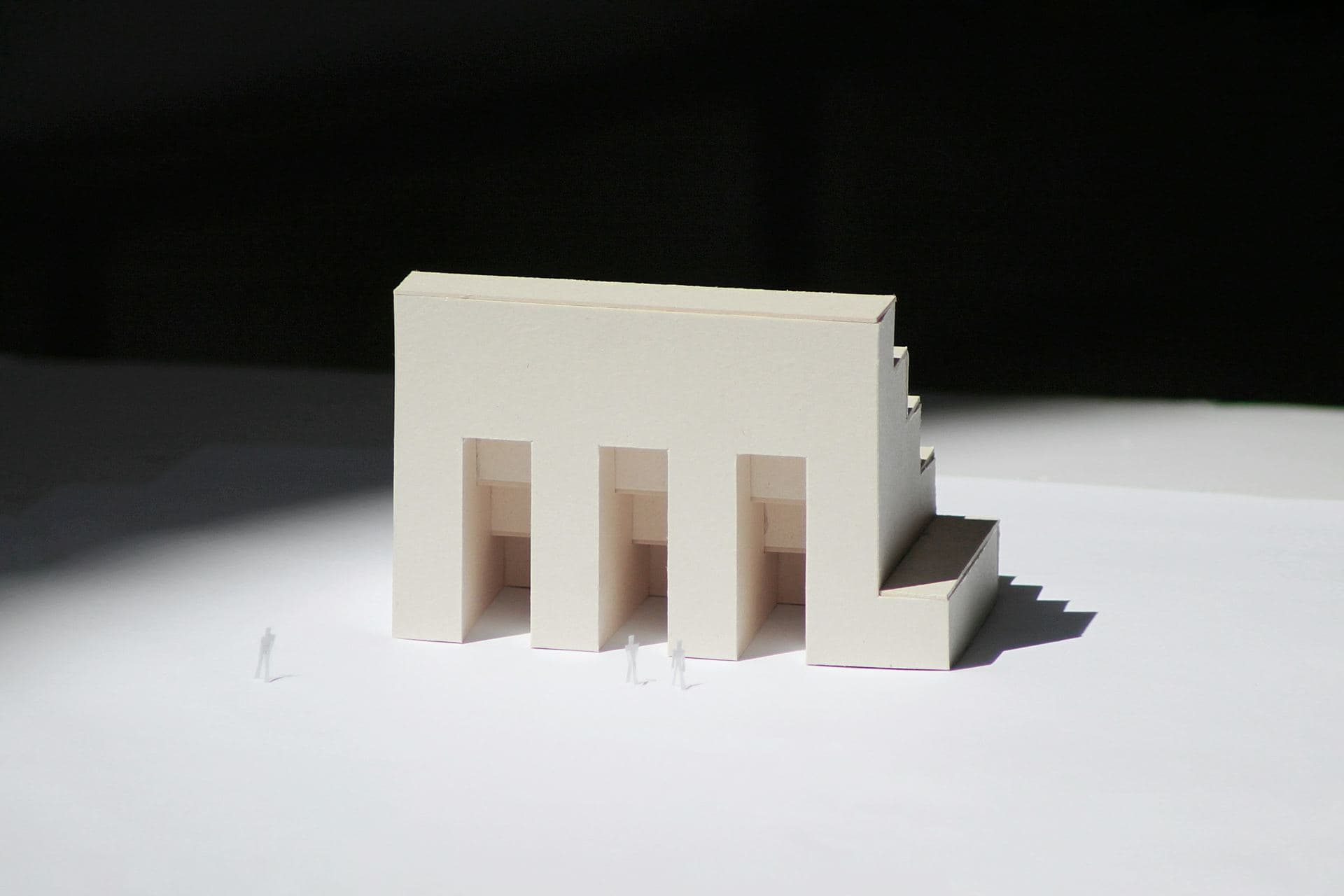 Maquette d'architecture en carton blanc, volume à arcades et gradins, éclairée en lumière rasante