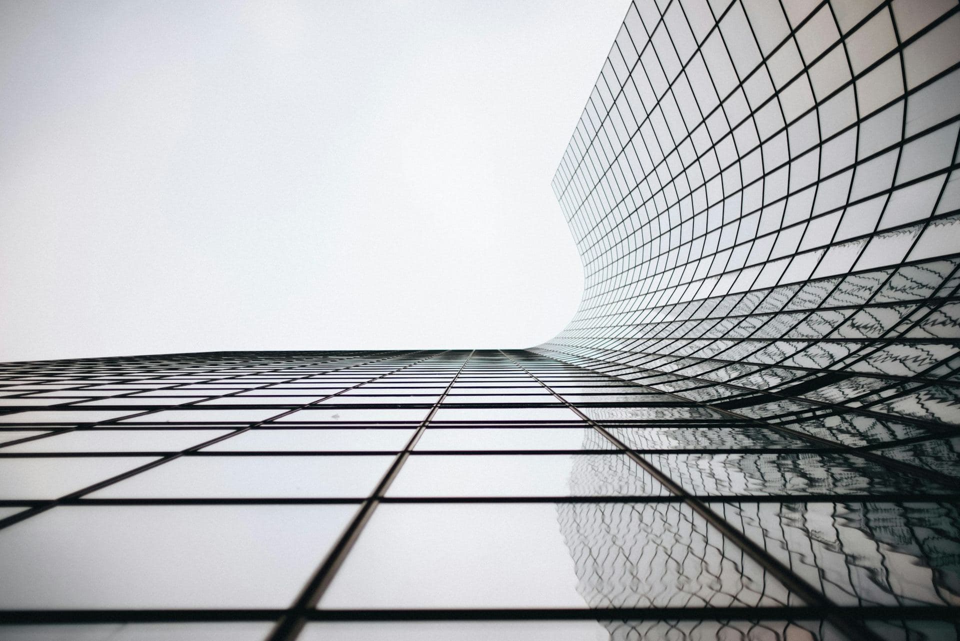 Façade de verre incurvée d'un immeuble de bureaux en contre-plongée, trame de lignes graphiques
