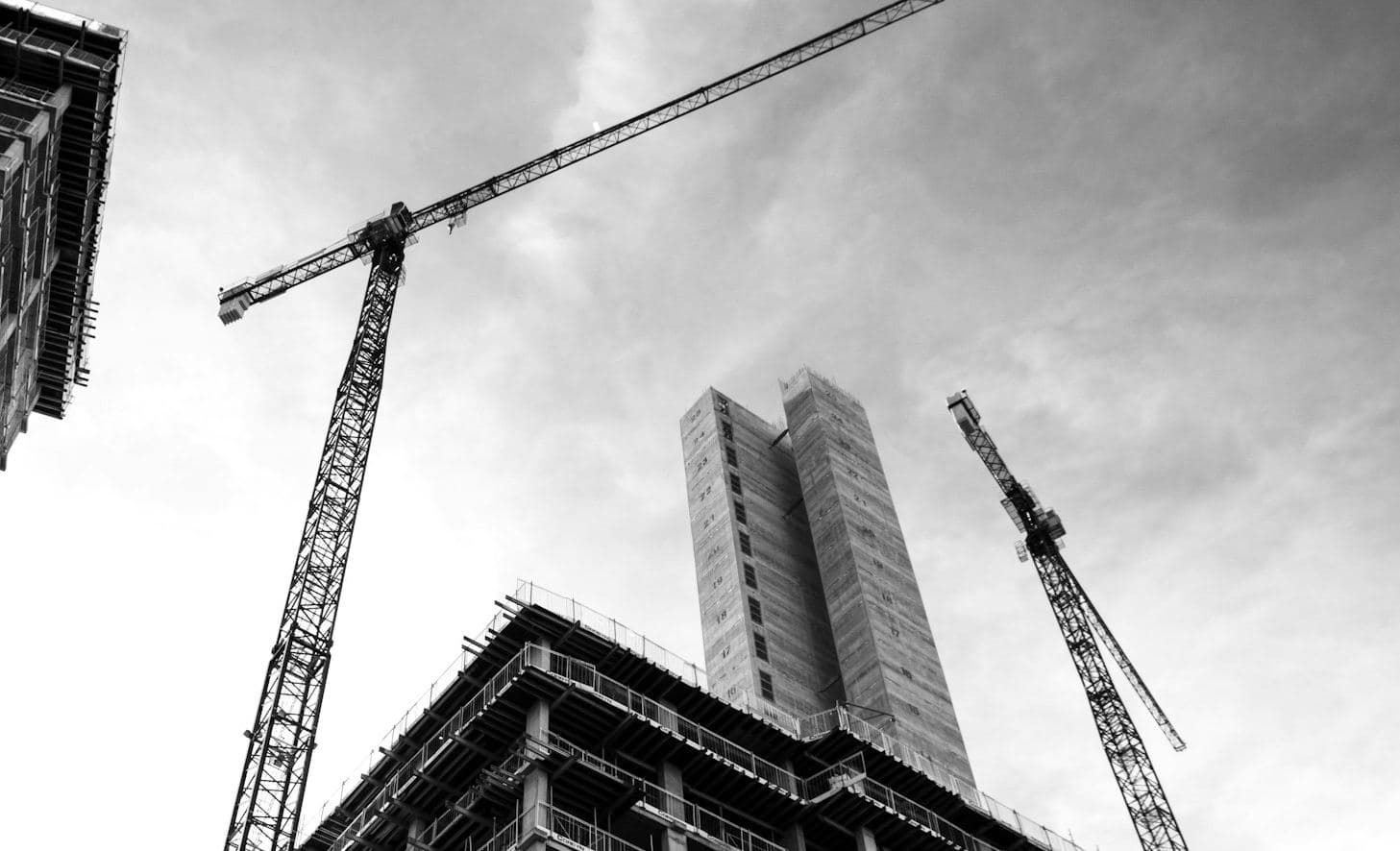 Grues à tour au-dessus d'une structure en béton en cours d'élévation, vue en contre-plongée