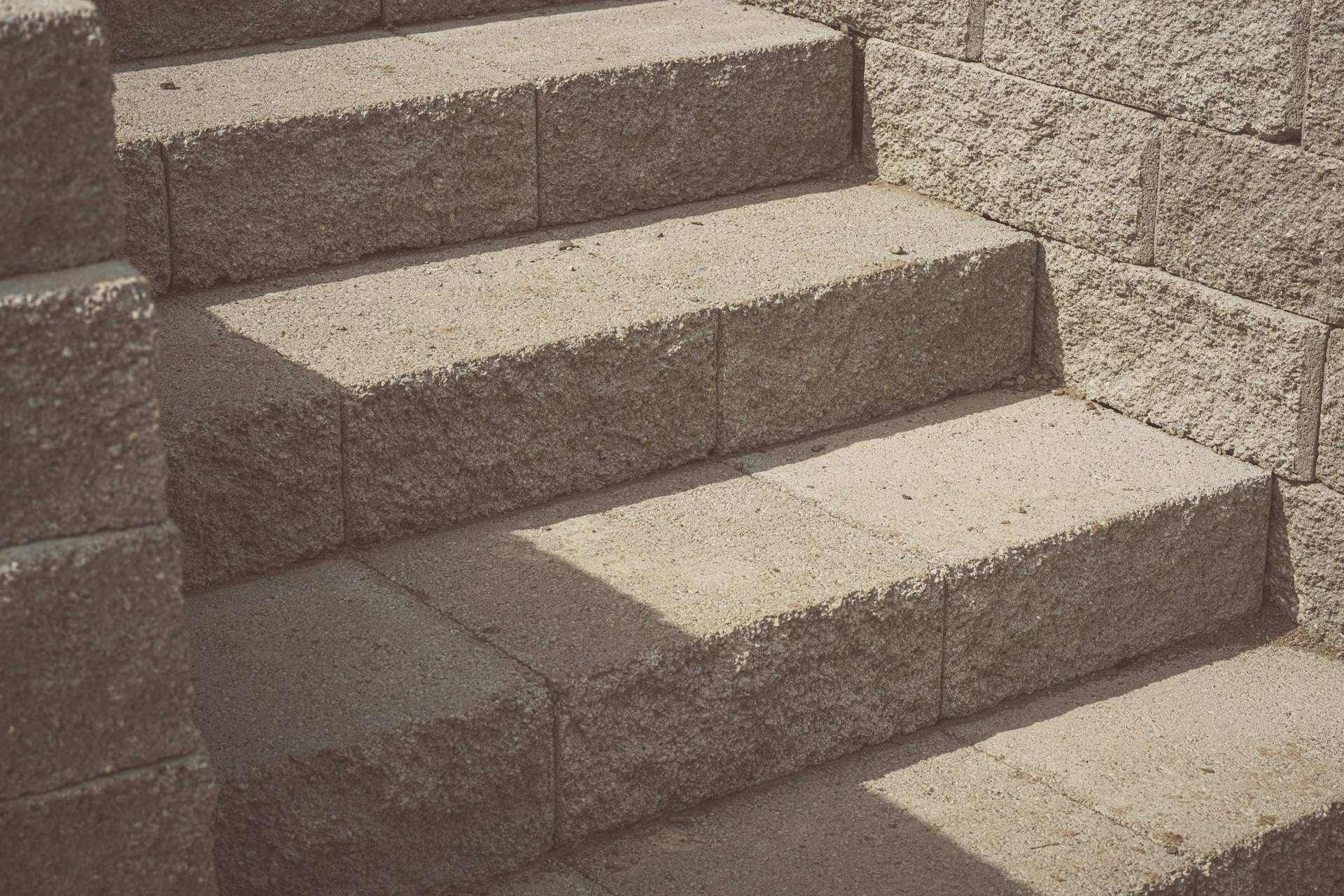 Marches en pierre taillée le long d'un mur en blocs, partagées entre ombre et lumière