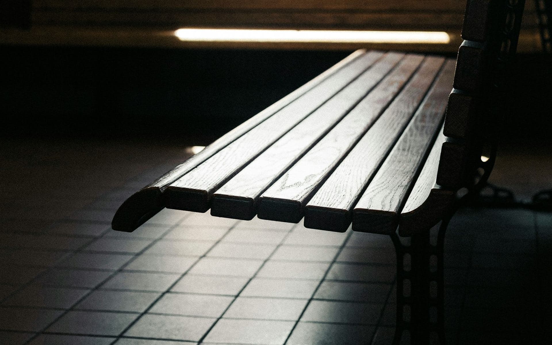 Banc de bois vide dans une salle d'attente, à contre-jour, sur un carrelage sombre