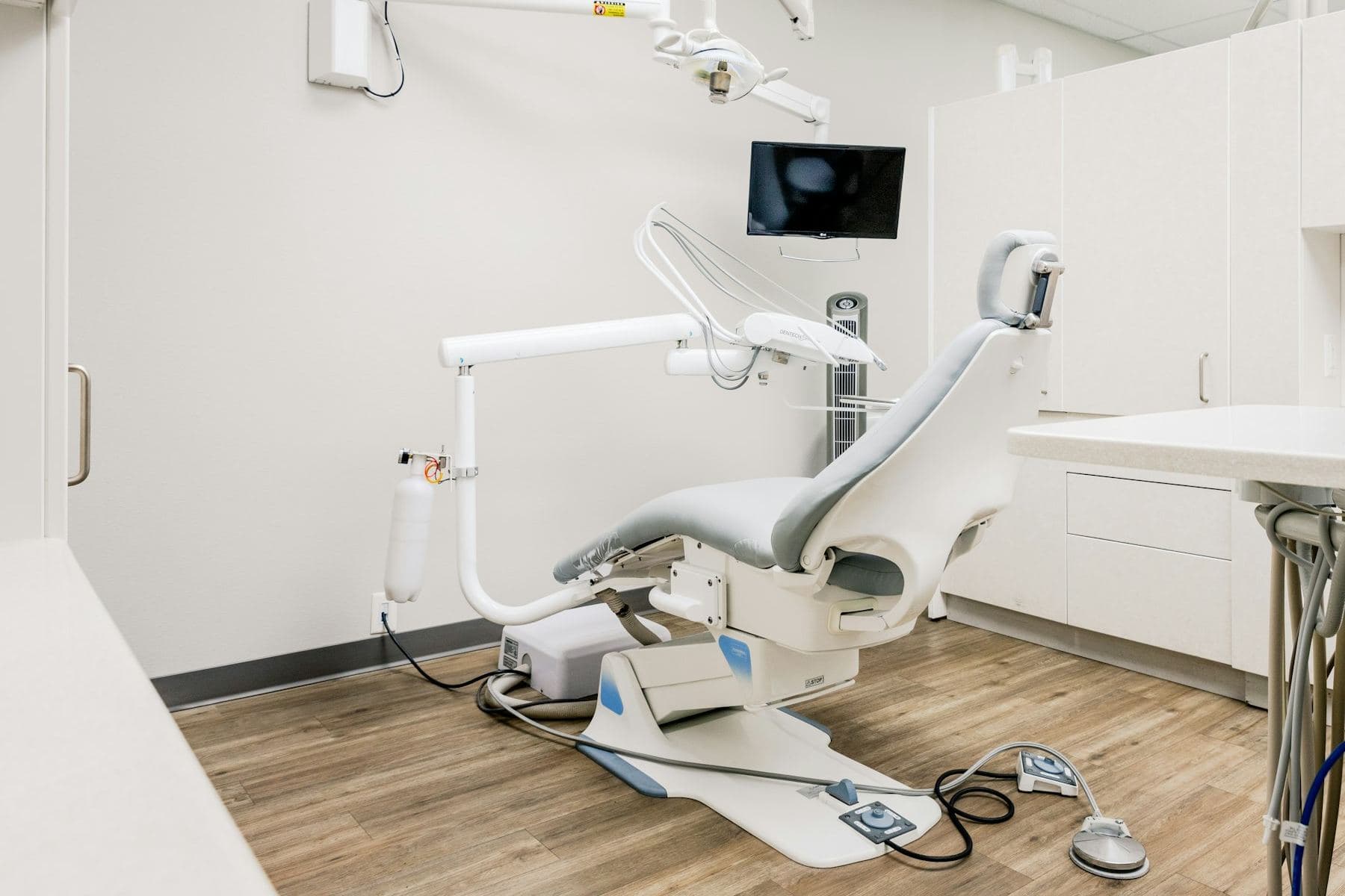Fauteuil dentaire inoccupé, scialytique et unit de soins dans un cabinet clair au parquet de bois